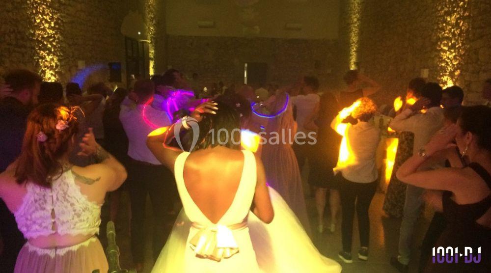 Groupe de personnes dansant dans une salle en pierre éclairée par des lumières colorées.