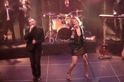 Miniature DJ Saint-Étienne-la-Thillaye (Calvados) - Tuxedo-prod #13 Scène de concert avec batterie, guitares, claviers et micros sous un éclairage coloré.