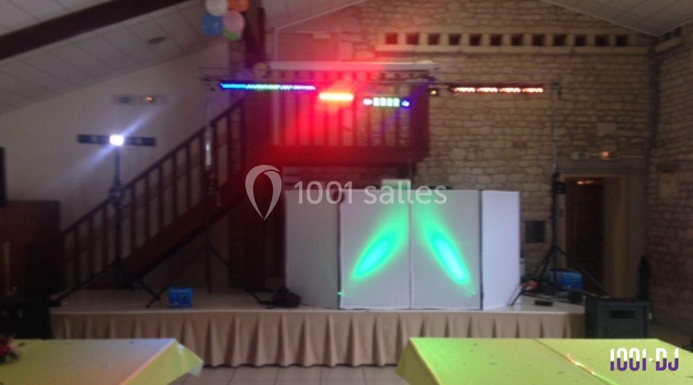 Installation de matériel de sonorisation et éclairage coloré dans une salle avec murs en pierre et plafond en bois.