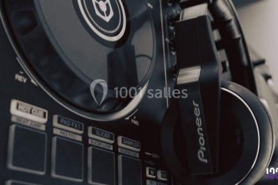 Un DJ mixant de la musique sur une table de mixage éclairée par des lumières colorées dans une ambiance nocturne.