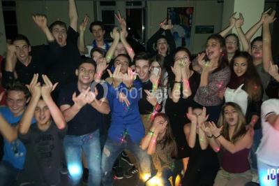 Un DJ mixant de la musique sur une table de mixage éclairée par des lumières colorées dans une ambiance nocturne.