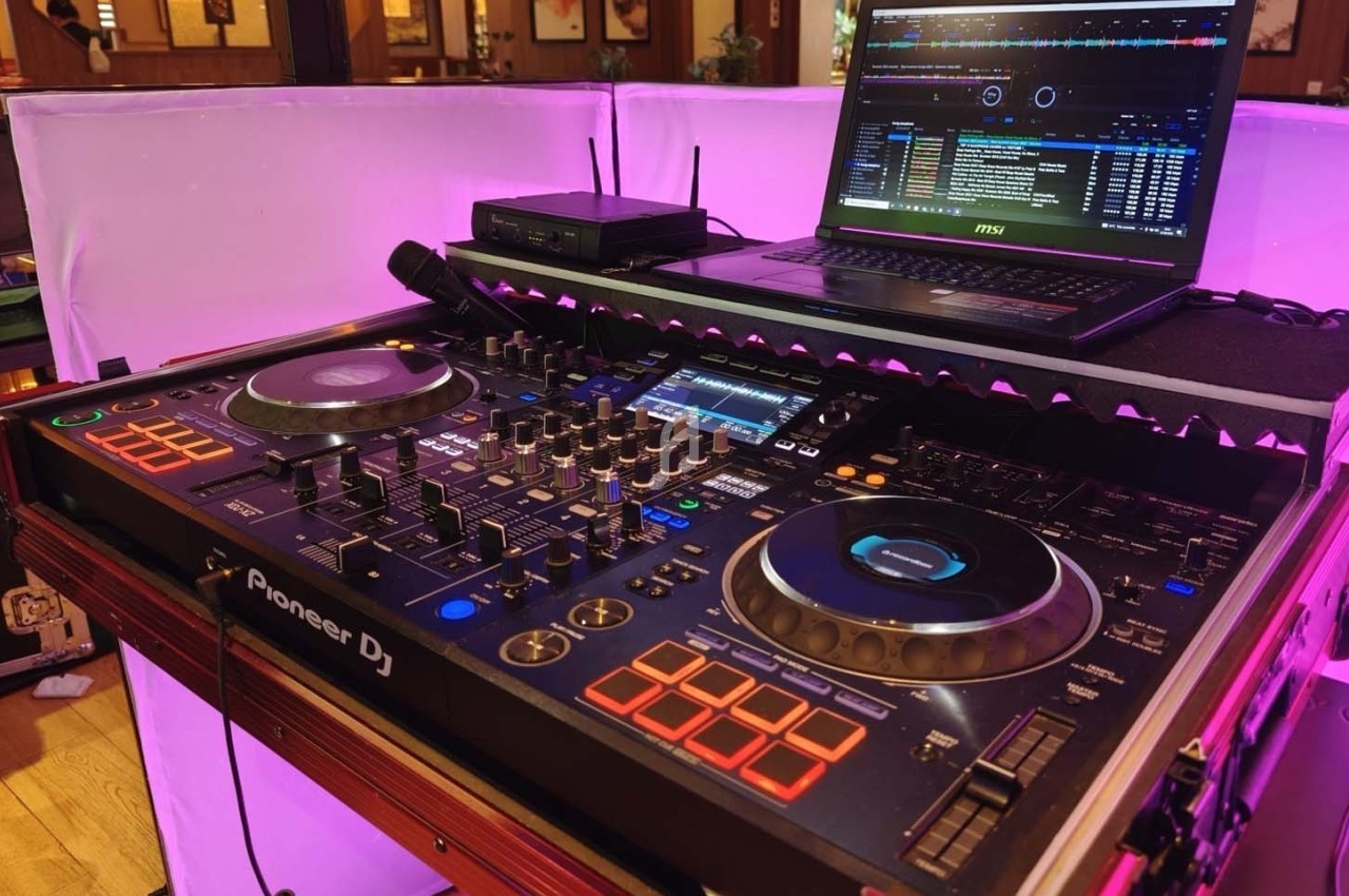 Console DJ Pioneer avec platines et contrôles, connectée à un ordinateur portable affichant un logiciel audio.