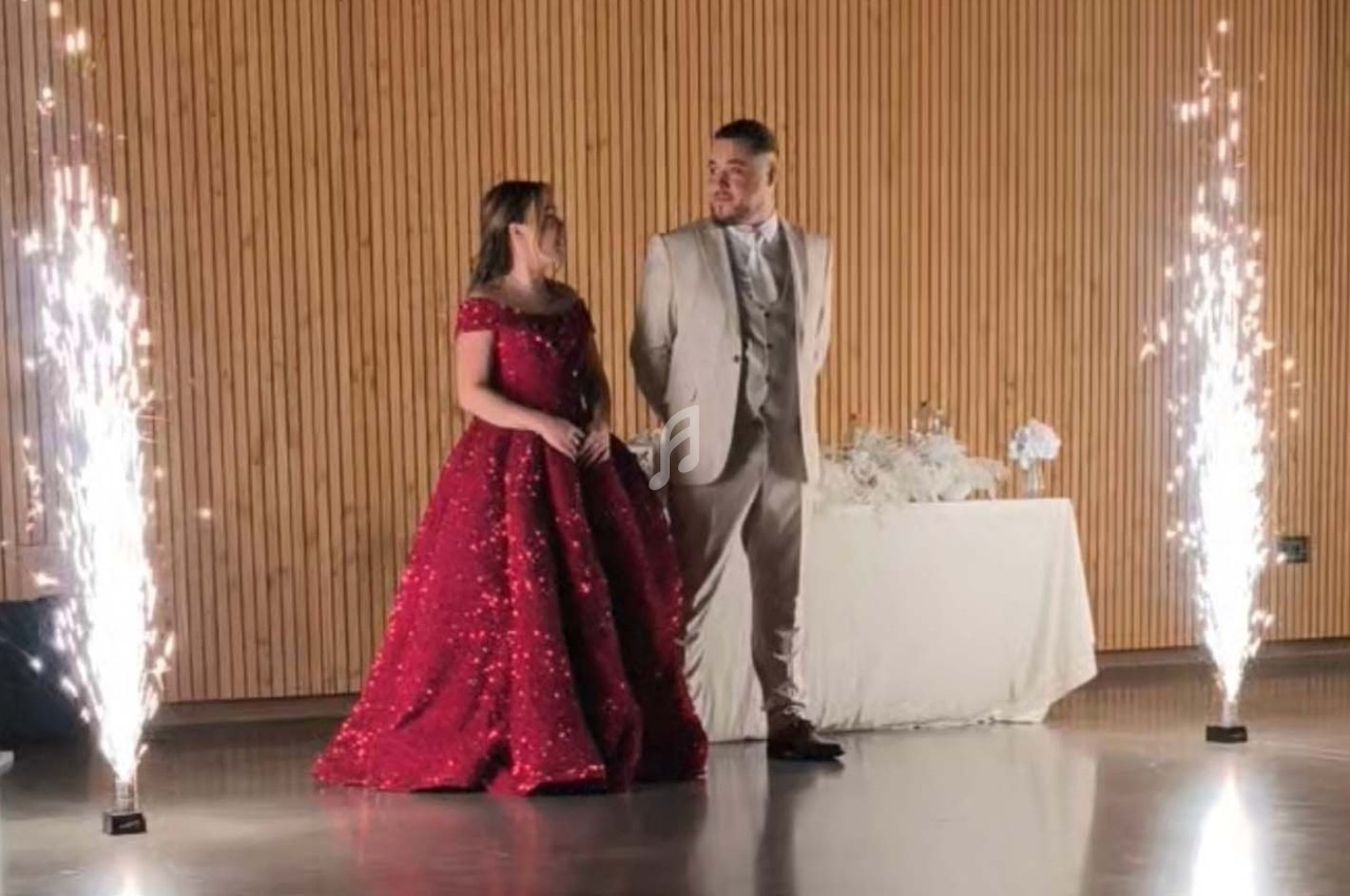 Un couple élégant se tient debout entre des fontaines d'étincelles dans une salle au mur en bois.