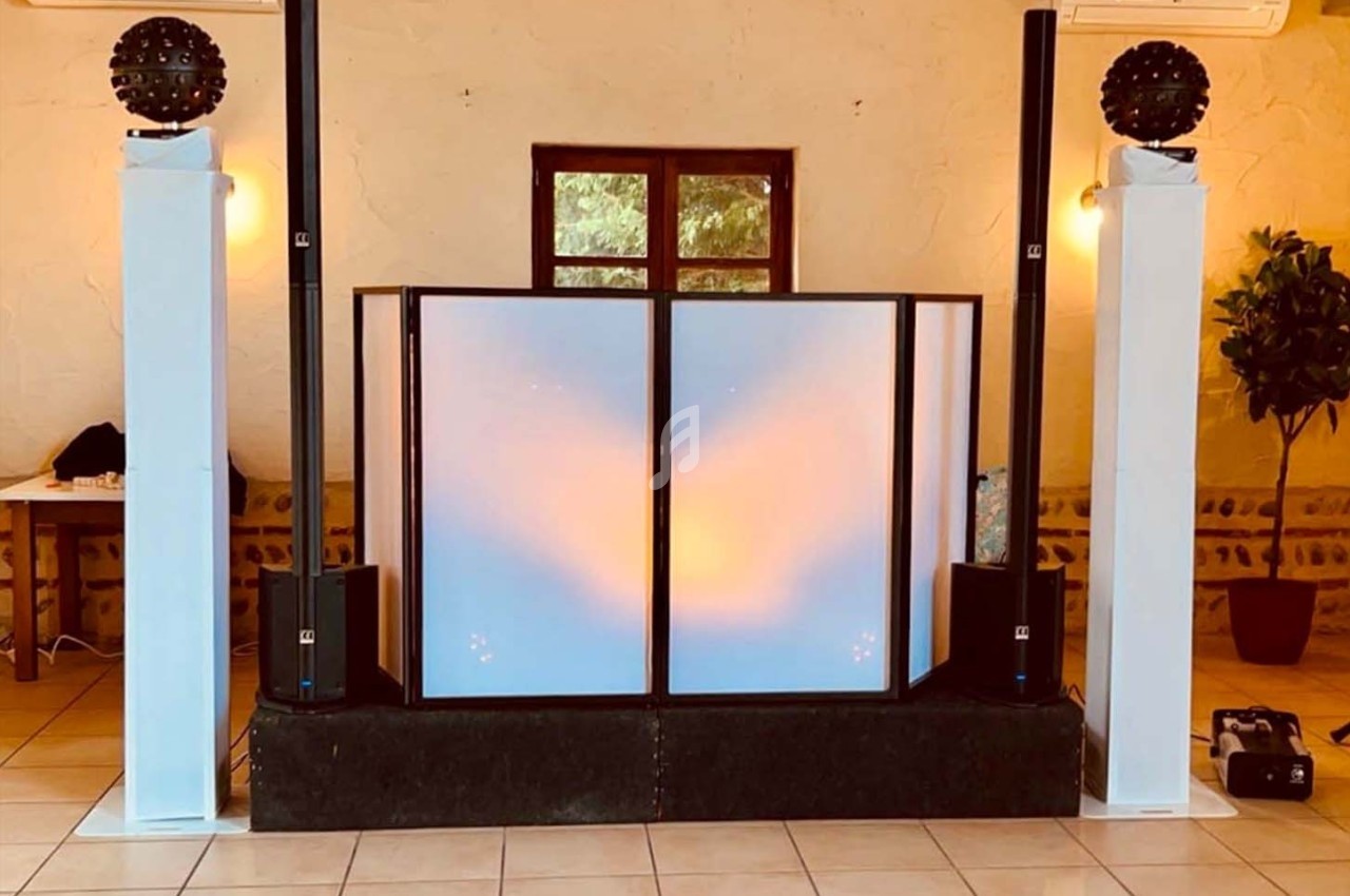 Installation de matériel de sonorisation et éclairage avec une cabine de DJ et des enceintes dans une salle.
