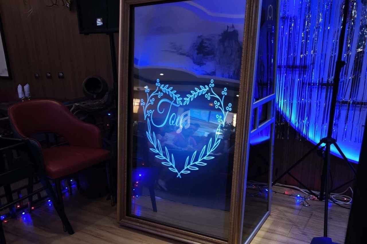 Miroir interactif encadré affichant un cœur lumineux avec le mot ’Love’, dans un décor intérieur éclairé en bleu.