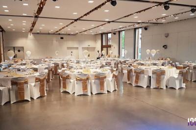 Salle de réception en plein air sous une verrière, avec tables décorées, nappes blanches et éclairage chaleureux.