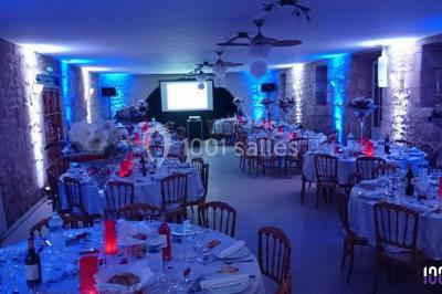 Salle de réception en plein air sous une verrière, avec tables décorées, nappes blanches et éclairage chaleureux.
