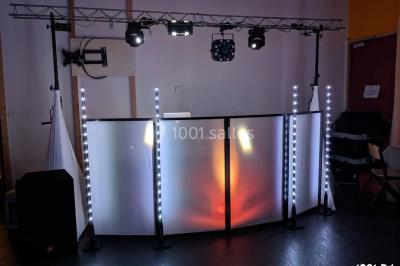 Salle de réception en plein air sous une verrière, avec tables décorées, nappes blanches et éclairage chaleureux.