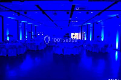 Salle de réception en plein air sous une verrière, avec tables décorées, nappes blanches et éclairage chaleureux.