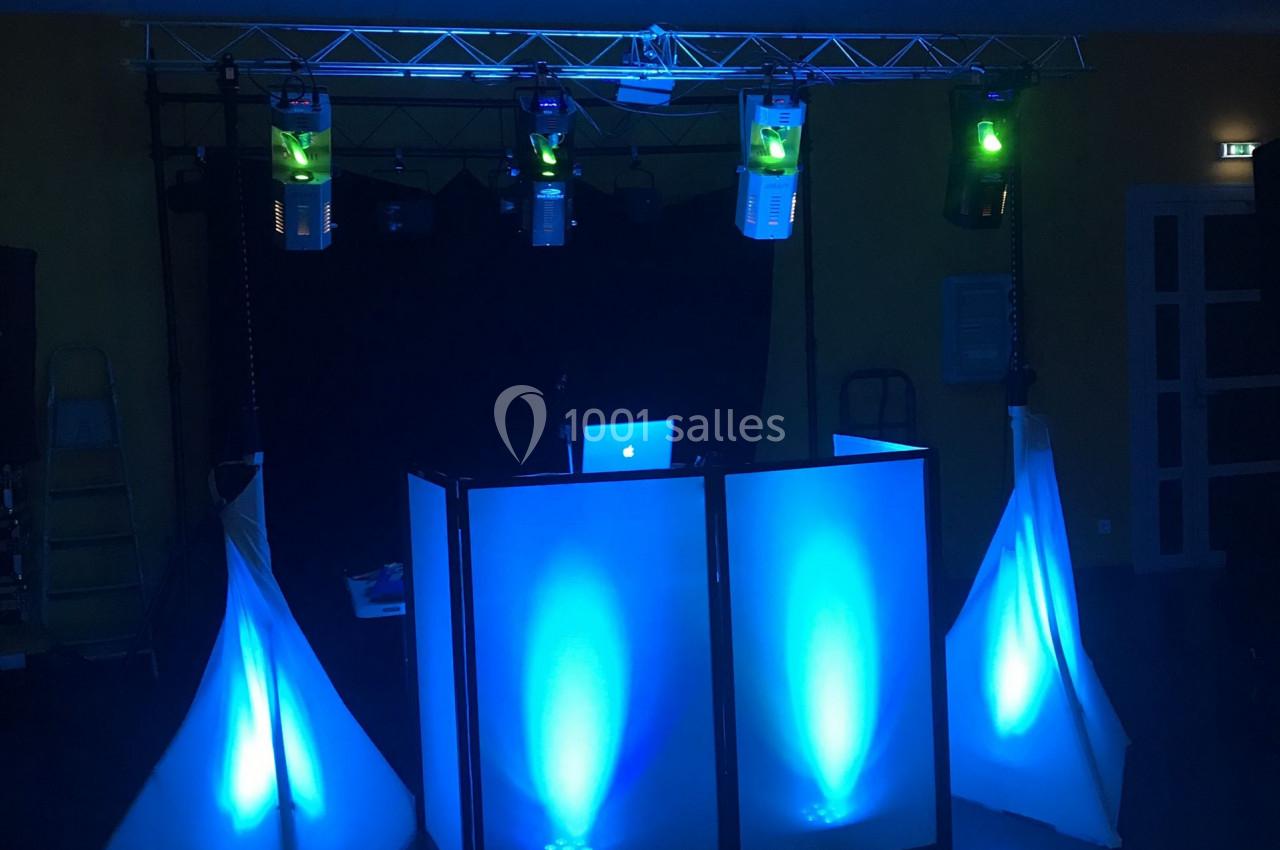 Installation de DJ avec éclairage bleu, comprenant une table de mixage et des spots lumineux dans une salle sombre.