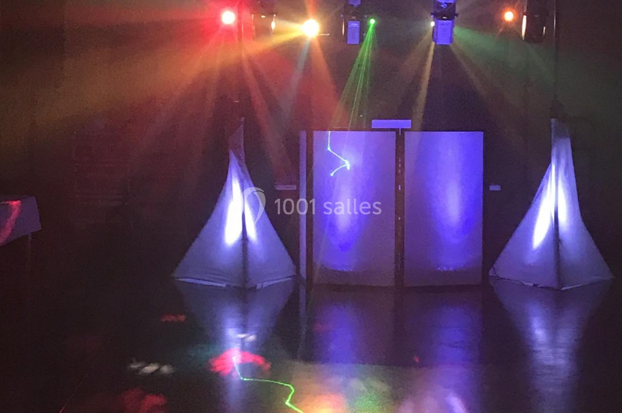 Jeu de lumières colorées projetées dans une salle sombre avec une installation de scène en arrière-plan.