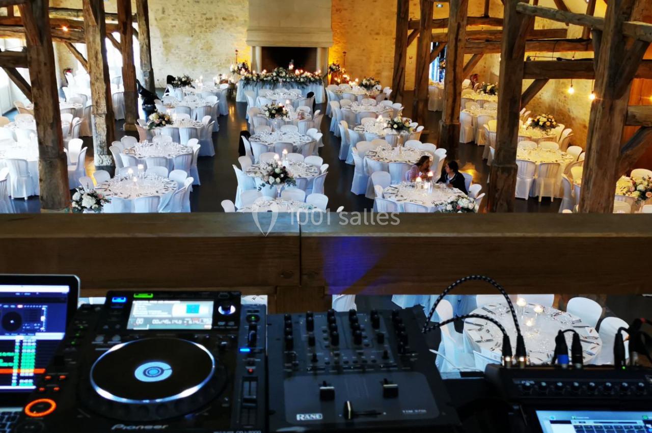 Salle de réception décorée pour un mariage, vue depuis une mezzanine avec une table de mixage au premier plan.