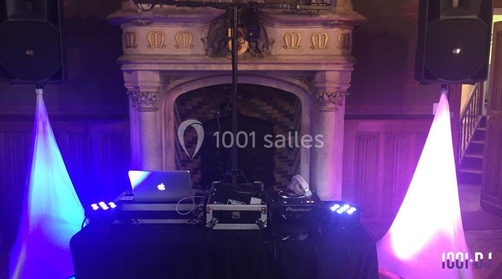 Équipement de DJ installé devant une cheminée décorative, avec éclairages colorés violet et blanc.