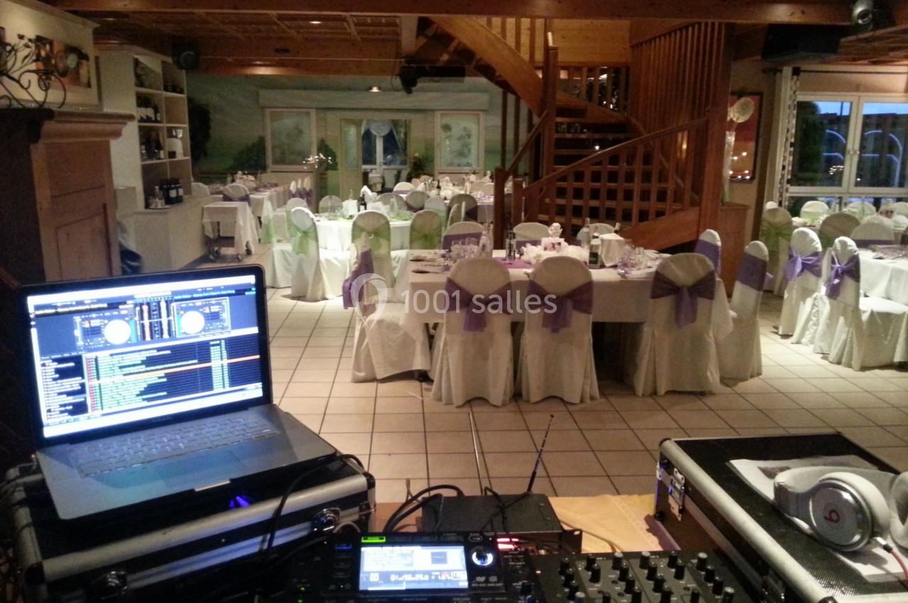 Salle de réception décorée avec des tables dressées, vue depuis une installation de DJ avec matériel audio.