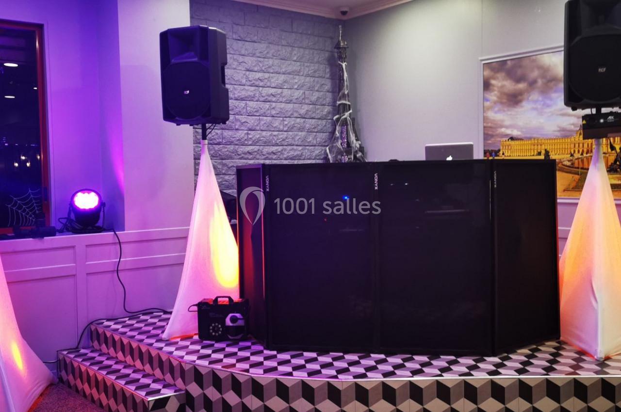 Configuration d'une scène avec une table de DJ, enceintes, éclairages colorés et décorations lumineuses.