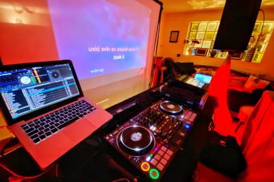 Miniature DJ Villiers-le-Bel (Val-d'Oise) - Gass Prod & Events #5 Console de DJ éclairée en bleu et rouge, installée dans une salle vitrée avec des invités en arrière-plan.