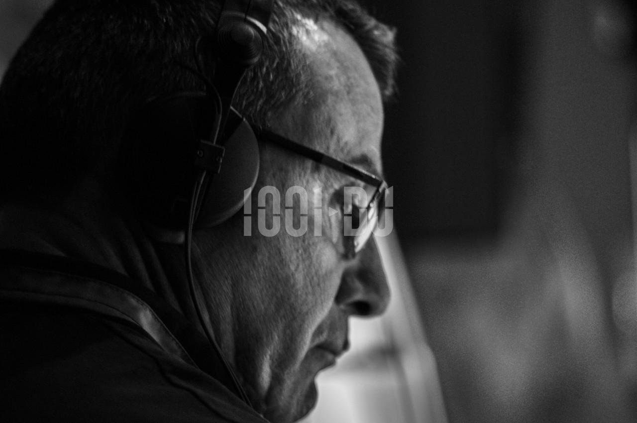 Homme portant un casque audio, vu de profil, concentré dans un environnement sombre en noir et blanc.