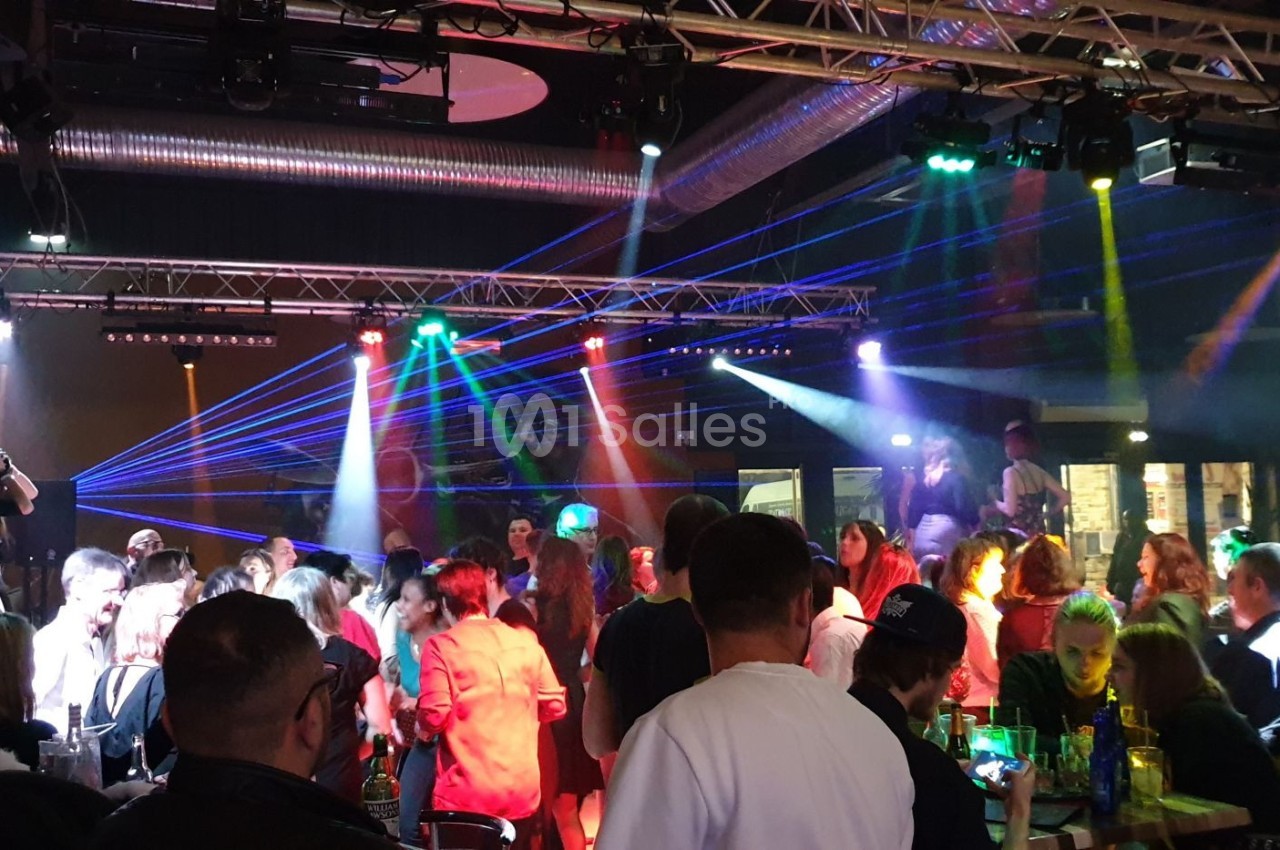 Groupe de personnes dans une discothèque avec jeux de lumières colorées et ambiance festive.