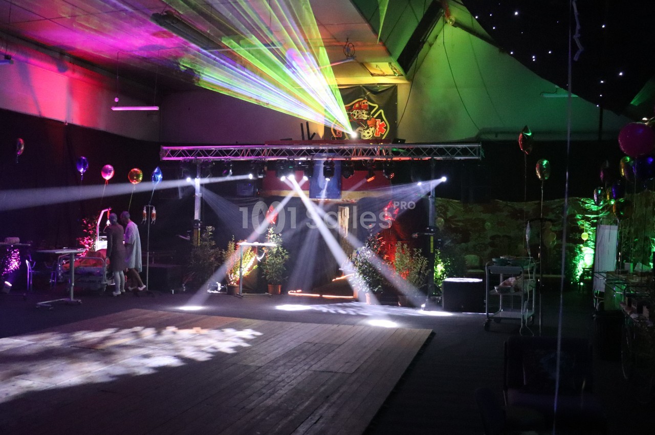 Salle décorée avec des lumières colorées, des lasers et des ballons, préparée pour un événement festif.