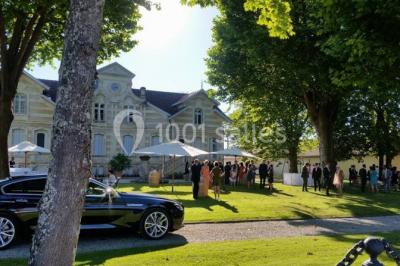 Table dressée avec des verres, tasses à café, un menu, un ordinateur portable ouvert et des chandeliers en arrière-plan.