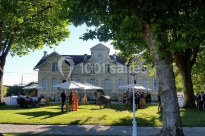 Table dressée avec des verres, tasses à café, un menu, un ordinateur portable ouvert et des chandeliers en arrière-plan.