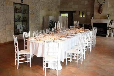 Table dressée avec des verres, tasses à café, un menu, un ordinateur portable ouvert et des chandeliers en arrière-plan.