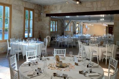 Table dressée avec des verres, tasses à café, un menu, un ordinateur portable ouvert et des chandeliers en arrière-plan.