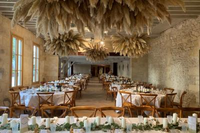 Table dressée avec des verres, tasses à café, un menu, un ordinateur portable ouvert et des chandeliers en arrière-plan.