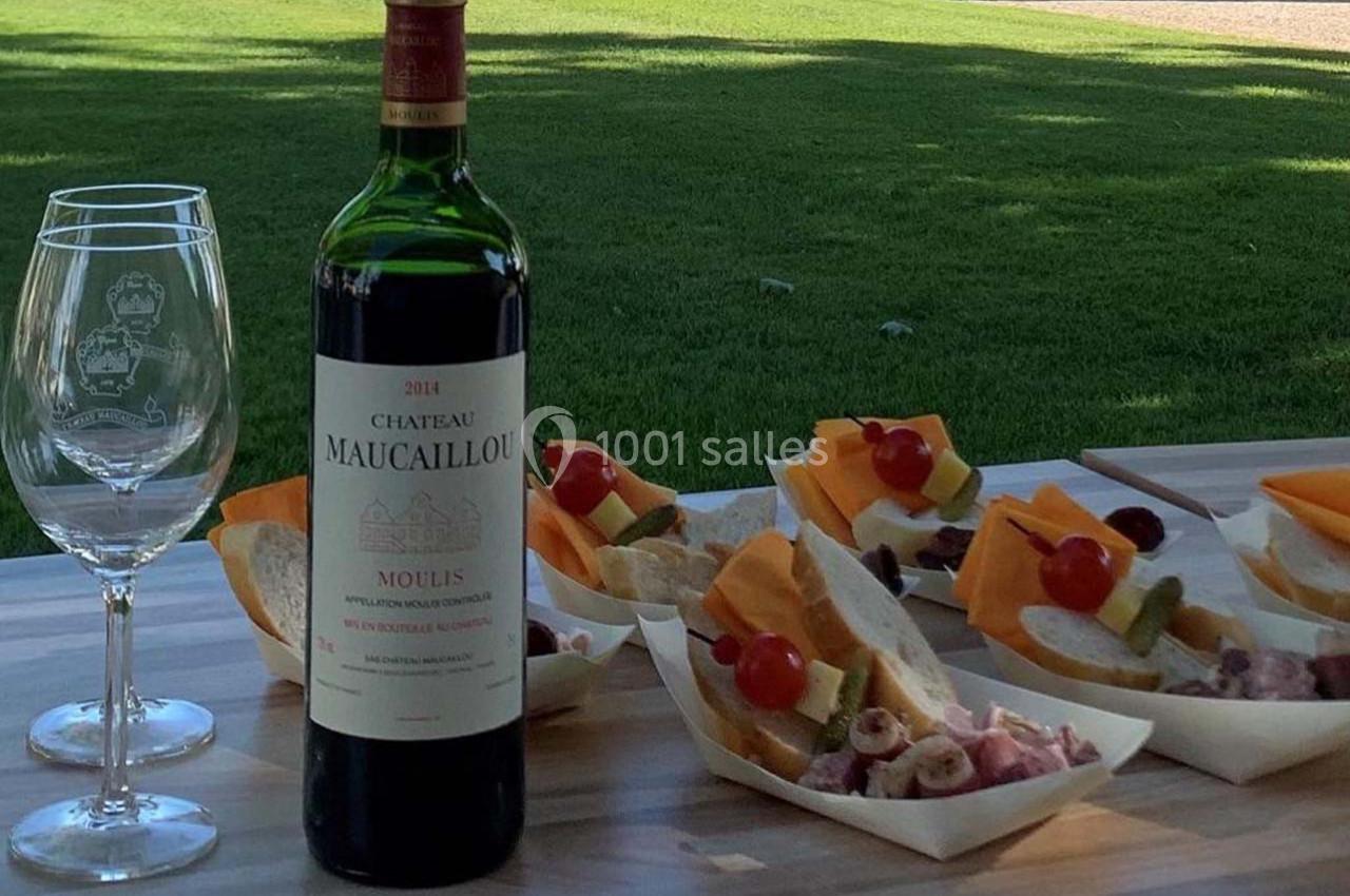 Bouteille de vin rouge avec deux verres et des plateaux de charcuterie et fromage sur une table en extérieur.