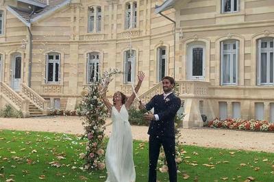 Table dressée avec des verres, tasses à café, un menu, un ordinateur portable ouvert et des chandeliers en arrière-plan.