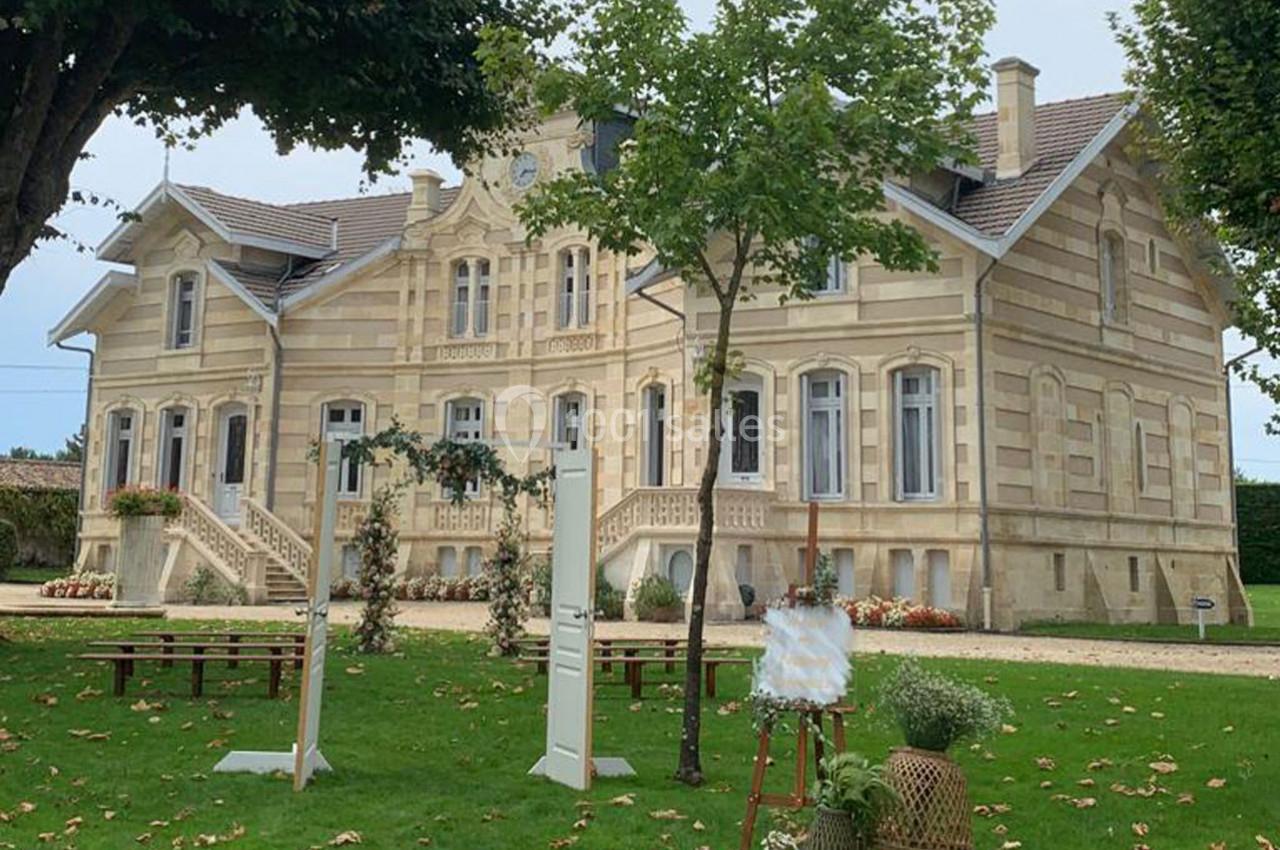 Grande maison en pierre de style classique entourée d'un jardin verdoyant avec des arbres et des décorations extérieures.