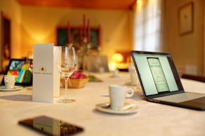 Table dressée avec des verres, tasses à café, un menu, un ordinateur portable ouvert et des chandeliers en arrière-plan.