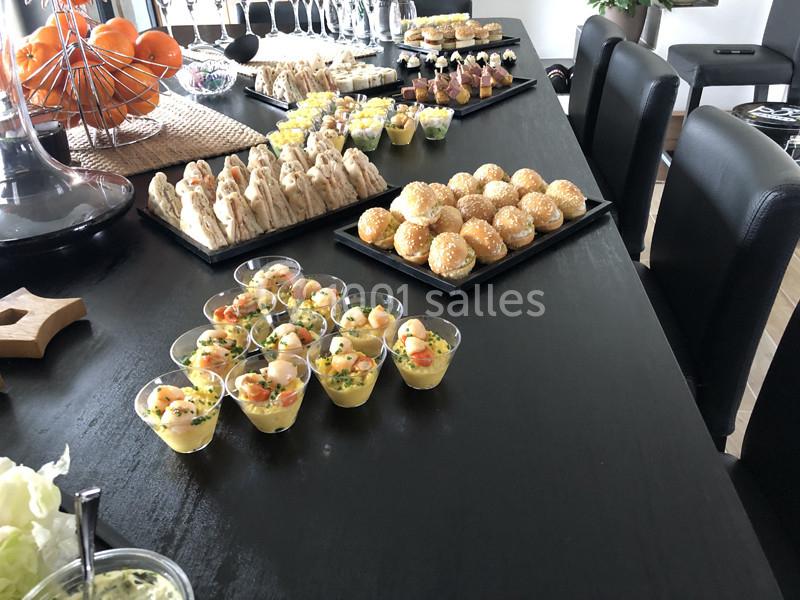 Table noire garnie de verrines, mini-burgers, sandwichs et desserts pour un buffet ou un apéritif.