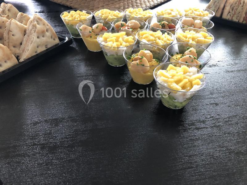 Plateau de verrines colorées contenant des morceaux de fruits et légumes, disposé sur une table sombre.