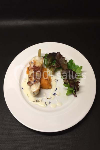 Brochette de poulet sur purée de patate douce, accompagnée de salade verte et sauce blanche, servie sur une assiette blanche.