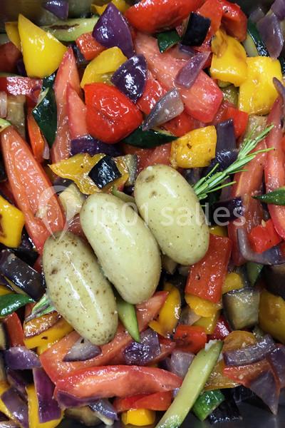 Légumes colorés coupés en morceaux avec trois pommes de terre entières, prêts pour une cuisson ou une préparation culinaire.
