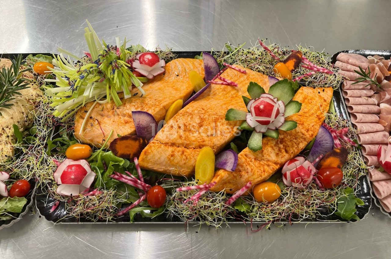 Filets de poisson assaisonnés présentés sur un lit de légumes frais et décorés de radis sculptés.