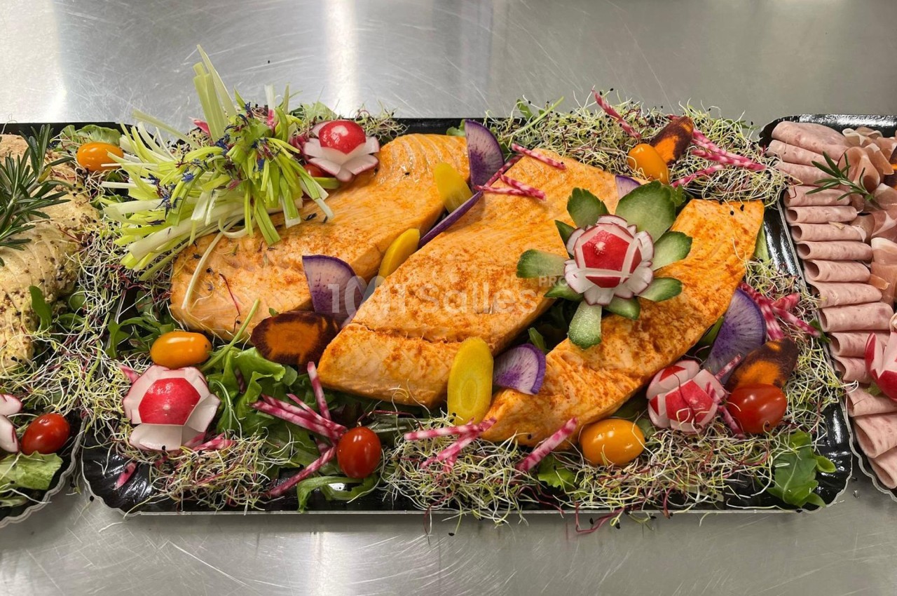 Filets de poisson assaisonnés présentés sur un lit de légumes frais et décorés de radis sculptés.