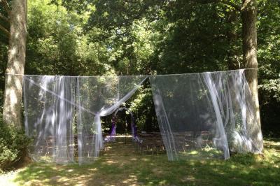 Texte ’Bienvenue à notre mariage’ écrit sur un miroir décoré de fleurs, reflétant un jardin verdoyant.