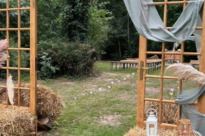 Texte ’Bienvenue à notre mariage’ écrit sur un miroir décoré de fleurs, reflétant un jardin verdoyant.