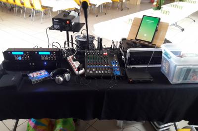 Salle décorée avec table dressée, matériel de sonorisation et panneau promotionnel pour des événements festifs.