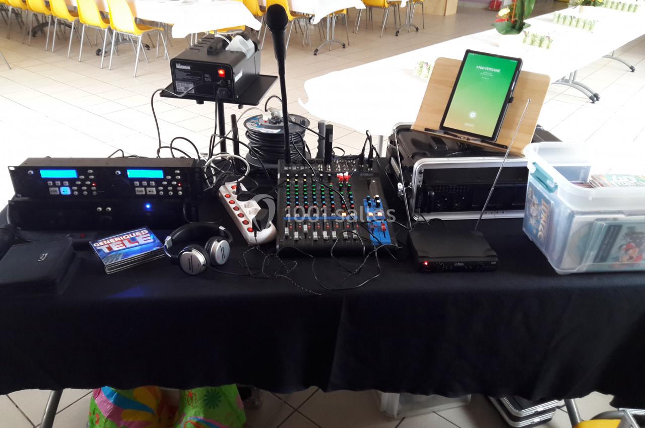 Matériel audio et vidéo installé sur une table, comprenant une console de mixage, un micro, un casque et divers équipements.