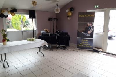 Salle décorée avec table dressée, matériel de sonorisation et panneau promotionnel pour des événements festifs.