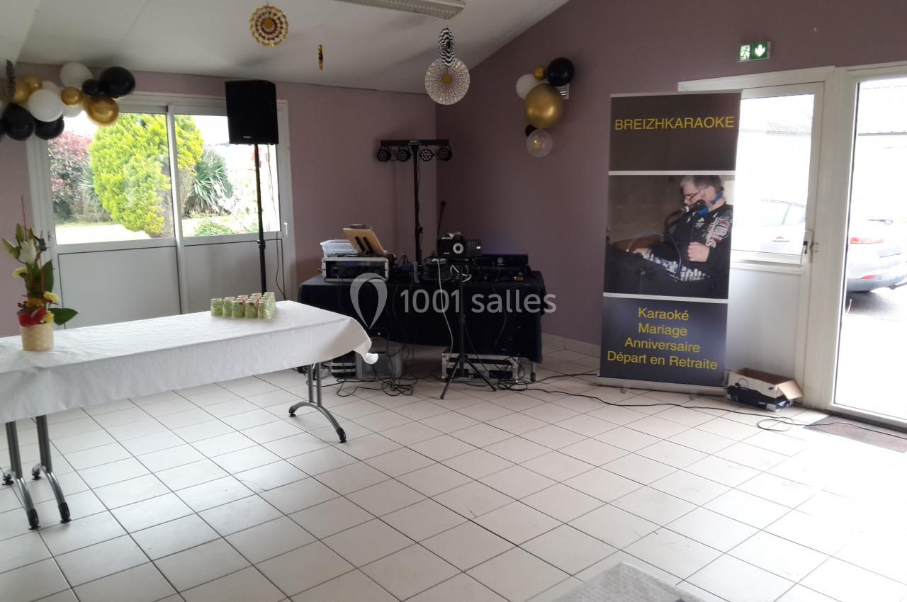 Salle décorée avec table dressée, matériel de sonorisation et panneau promotionnel pour des événements festifs.