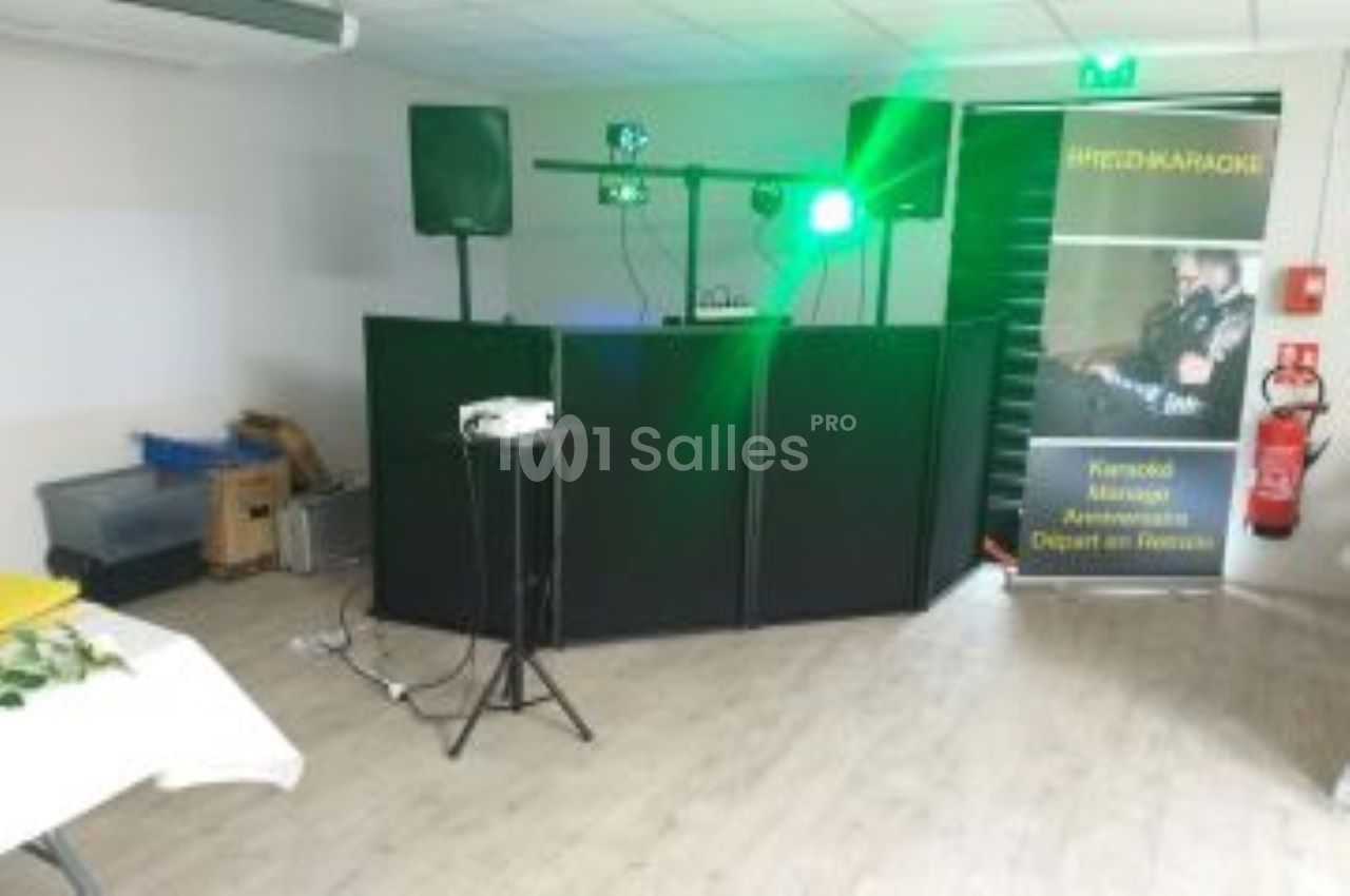 Installation de matériel de sonorisation et d'éclairage dans une salle, avec une bannière publicitaire en arrière-plan.