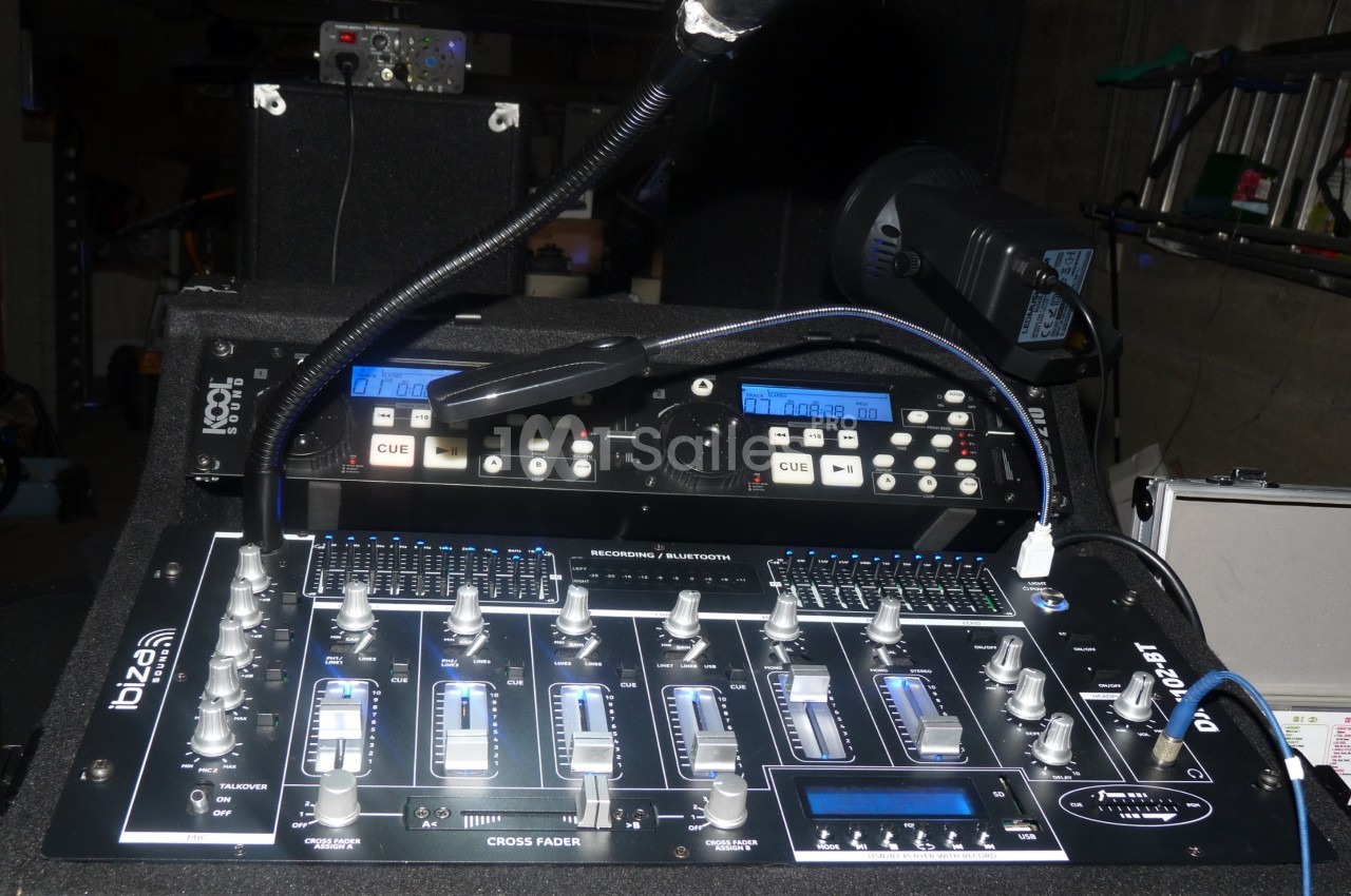 Table de mixage audio avec curseurs, boutons et micros, installée dans un environnement technique.