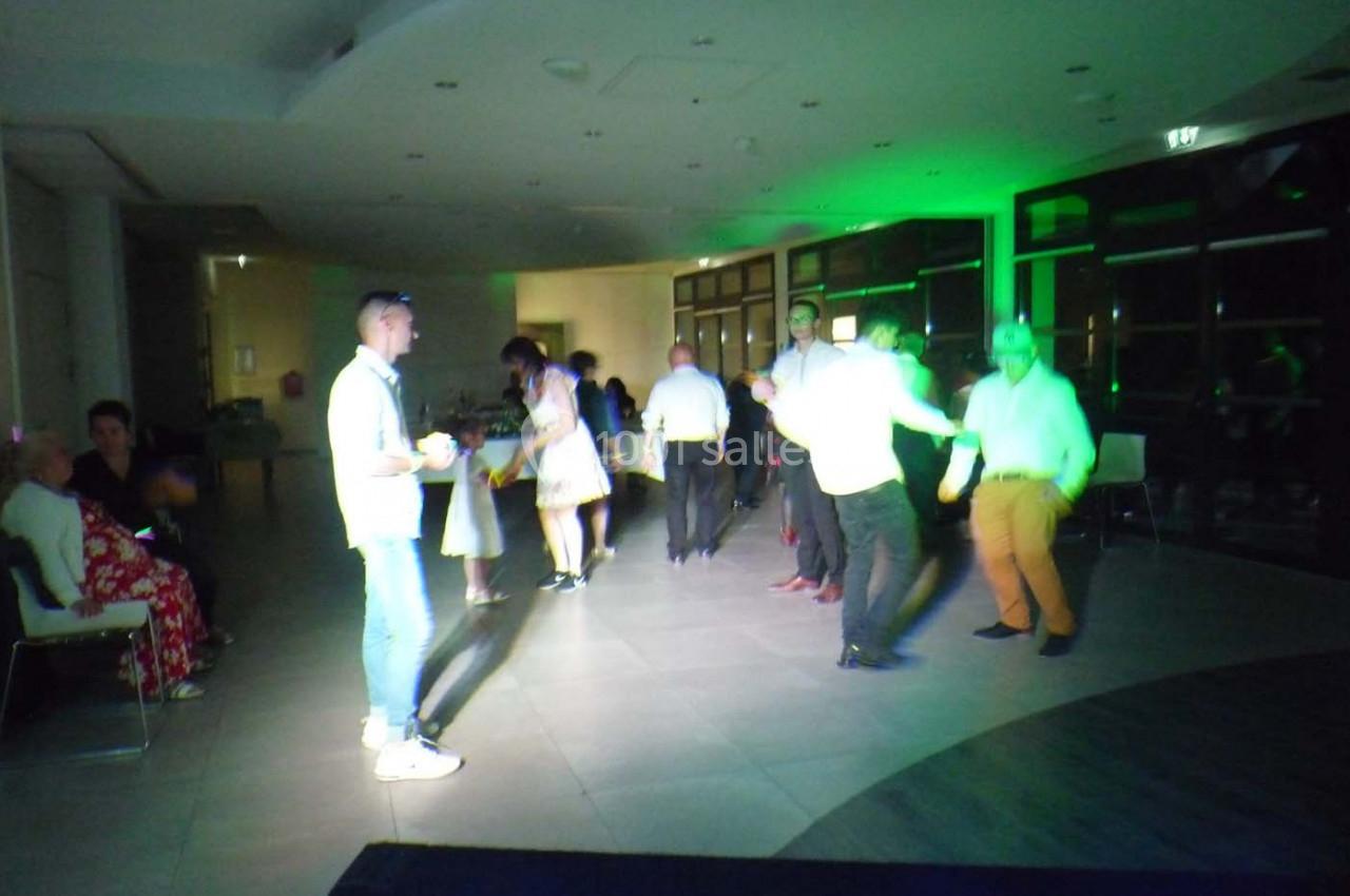 Personnes dansant et discutant dans une salle éclairée par des lumières colorées, ambiance festive.