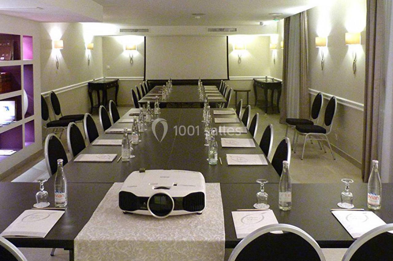 Salle de réunion équipée avec une grande table, chaises noires, projecteur et documents disposés pour une présentation.