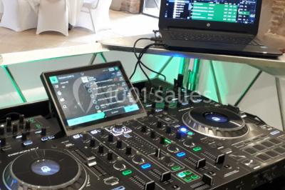 Salle de réception décorée avec des lumières colorées, des lanternes suspendues et un espace pour la musique et la danse.