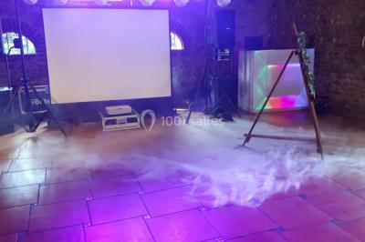 Salle de réception décorée avec des lumières colorées, des lanternes suspendues et un espace pour la musique et la danse.